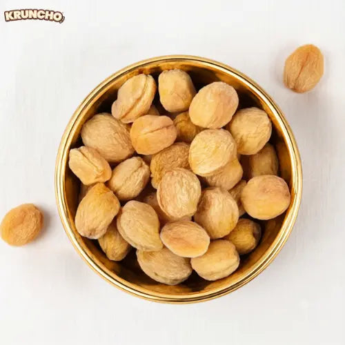 A golden bowl full of premium dried apricots.
