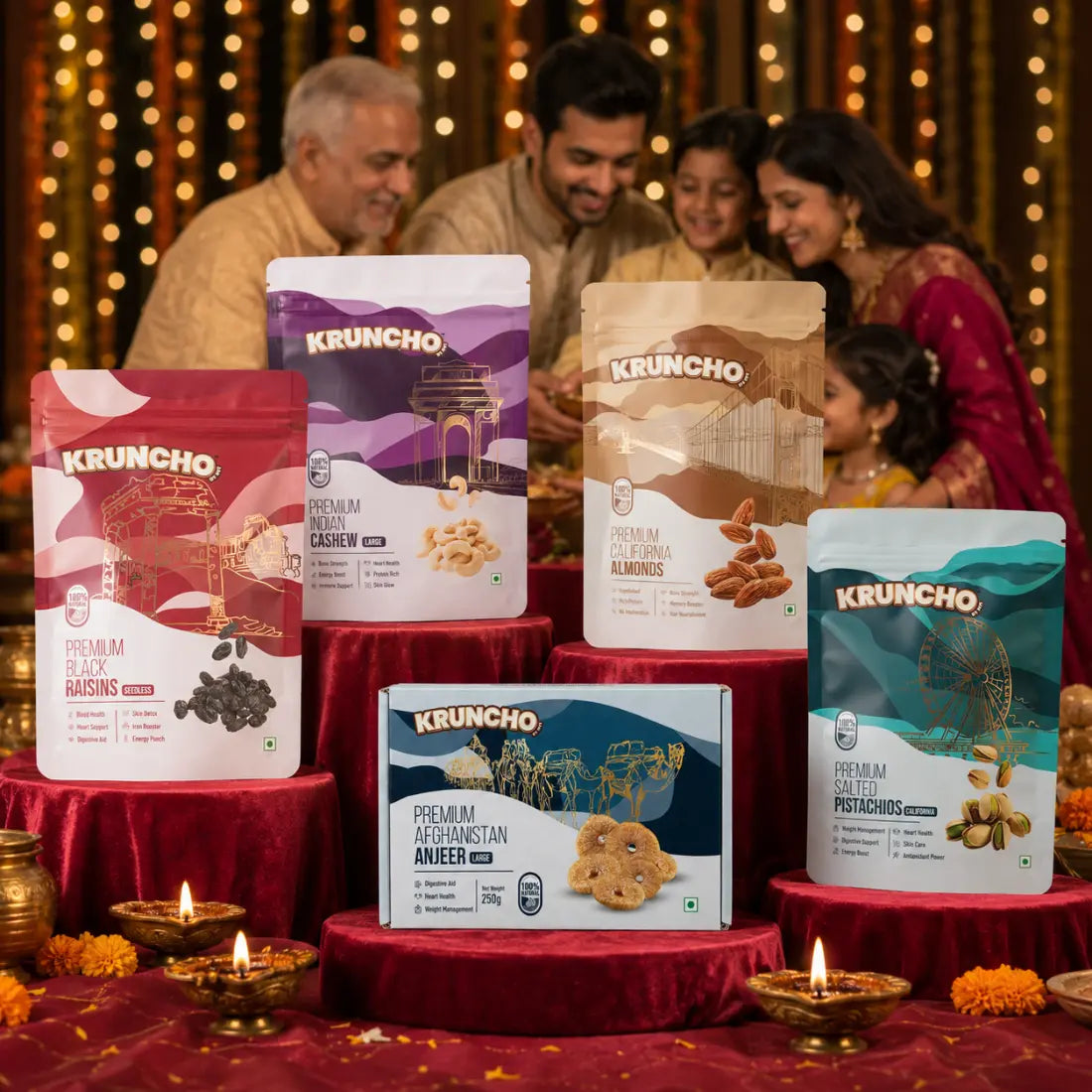A display of Kruncho premium dry fruit packets and gift boxes on red velvet pedestals with lit diyas, with a happy family celebrating in the softly blurred background.