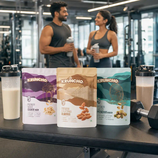 Kruncho Cashew, Almond, and Salted Pistachio pouches placed on a gym bench alongside protein shakers and dumbbells, with a fitness couple chatting in the background.