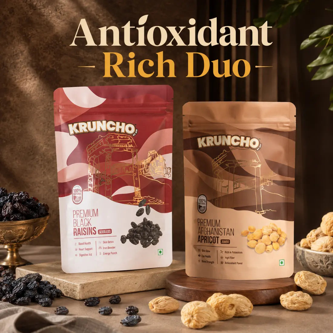 Packages of Kruncho Premium Black Raisins and Afghanistan Apricots sit on rustic wooden and stone risers, surrounded by loose raisins and dried apricots under the headline "Antioxidant Rich Duo".