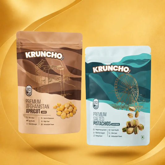 Two standing pouches of Kruncho healthy snacks: Premium Afghanistan Apricot Jumbo and Premium Salted Pistachios California against a gold background
