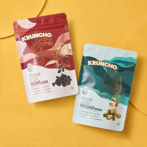 Two pouches of Kruncho brand snacks, featuring Premium Black Raisins and Premium Salted Pistachios, arranged side-by-side on a bright yellow background.