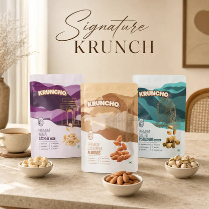 "Signature KRUNCH" trio featuring pouches of Indian Cashews, California Almonds, and Salted Pistachios set on a countertop with matching bowls of nuts.