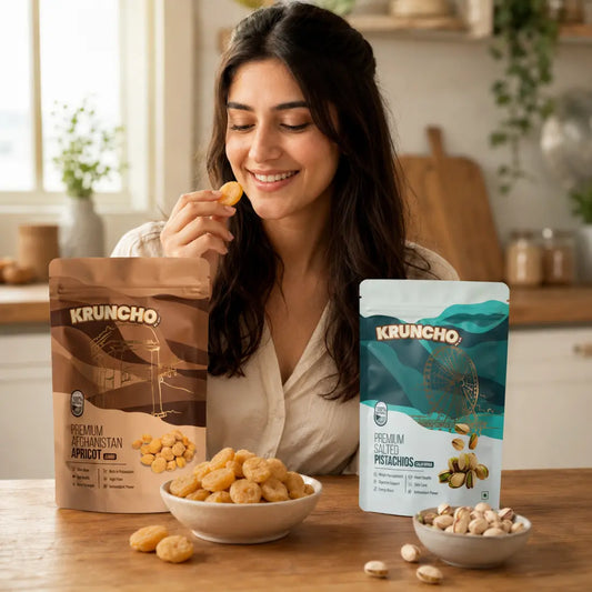 A woman enjoying Kruncho 100% natural healthy snacks, featuring Premium Jumbo Afghanistan Apricot and Salted California Pistachios packages.